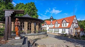 Ein traditionelles Fachwerkhäuschen mit Steinbau und einer Statue davor.