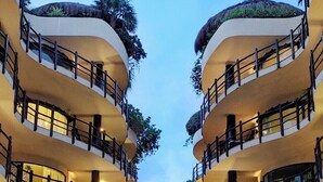 A hotel with a central pool, multiple balconies, and lush greenery. - Ocean view Condo, Large Private balcony over beach with jacuzzi, 2 pools, W/D (Playa del Carmen)