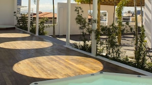 A rooftop pool area with circular skylights, palm trees, and a view of buildings in the background.