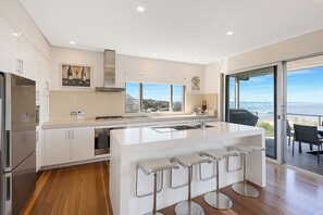 A modern kitchen with a central island, stainless steel appliances, and a view to the outside.