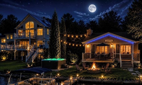 A waterfront property with a large house, a separate building labeled 'SUNRISE,' outdoor seating, and a fire pit.. Campau Lake Sunrise Retreat | Peaceful Lakefront