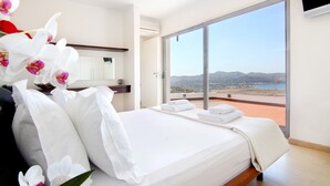 Ein Hotelzimmer mit einem großen Bett, Blick auf die Landschaft und einem an der Wand befestigten Flachbildfernseher.