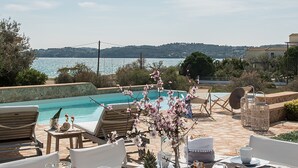 A table set for breakfast with a view of a swimming pool and the sea. - Villa Gold in Petrothalassa (Porto Cheli)