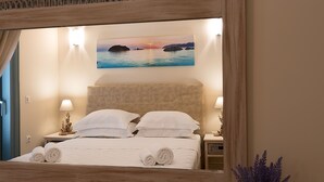 A hotel room with a bed, two bedside lamps, a painting of a sunset over water, and a potted plant. - Villa Gold in Petrothalassa (Porto Cheli)