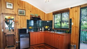 A kitchen with wooden cabinets, a microwave, and a sink. - Clouds on Beechmont - Chalet (Beechmont)