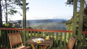 A wooden deck with a table and chairs, overlooking a forested valley with a misty background. - Clouds on Beechmont - Chalet (Beechmont)