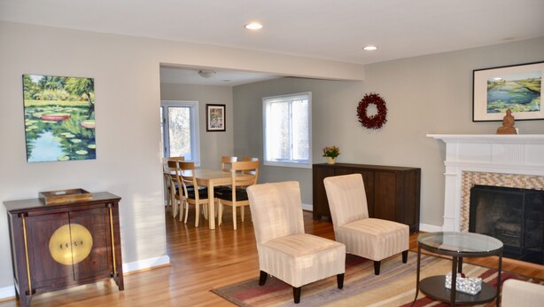 A living room with a fireplace, a dining area with chairs, and a painting on the wall. - Modern 3BR/2BA, Free parking, 9 miles to DC, minutes to 395-495 (Alexandria)