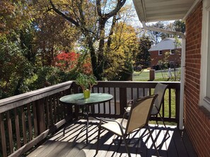 Enjoy a peaceful outdoor space with a deck, table, and chairs overlooking a residential area with trees and a nearby building.