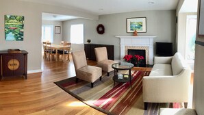 A living room with a fireplace, a dining area, and a hallway leading to another room. - Modern 3BR/2BA, Free parking, 9 miles to DC, minutes to 395-495 (Alexandria)
