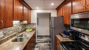 A kitchen with wooden cabinets, granite countertops, a stainless steel refrigerator, and a built-in oven. - Beachcomber unit 303 (Longboat Key)