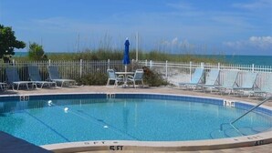 A pool with clear blue water, surrounded by lounge chairs and a white fence. - Beachcomber unit 303 (Longboat Key)