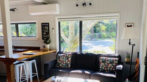 En moderne stue med sofa, sofabord og spiseplads med barstol.