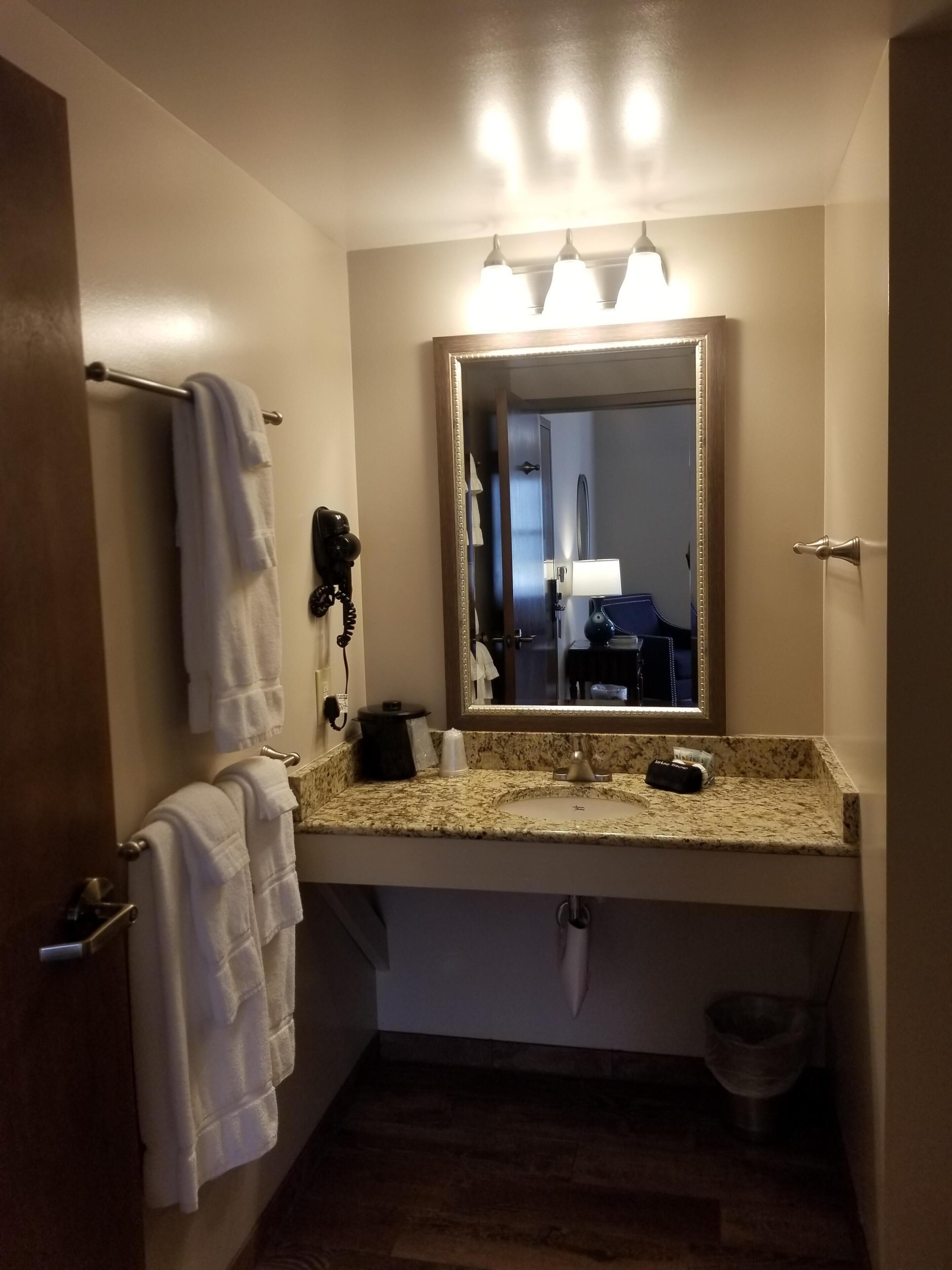 A bathroom with a sink, mirror, towel rack, and a telephone.
