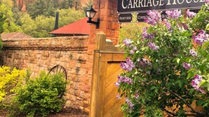 A sign for "Carriage House" with a wooden fence and a red roof. - Glen Eyrie Castle & Conference Center A Ministry of the Navigators (Colorado Springs)