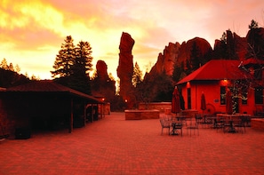 A courtyard with a red-roofed building, stone pillars, and outdoor seating. - Glen Eyrie Castle & Conference Center A Ministry of the Navigators (Colorado Springs)
