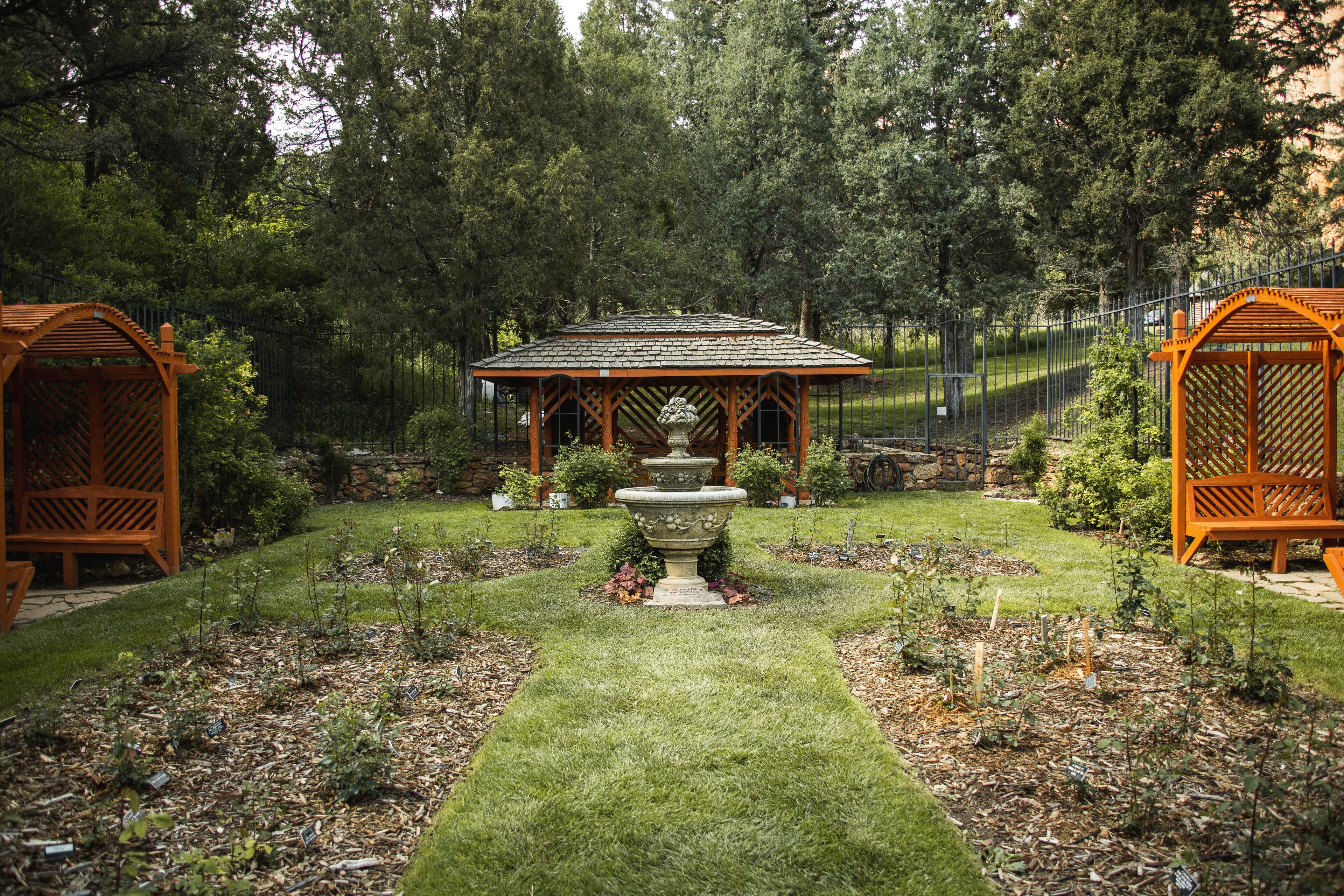 A garden with a gazebo, a central fountain, and a well-maintained lawn.