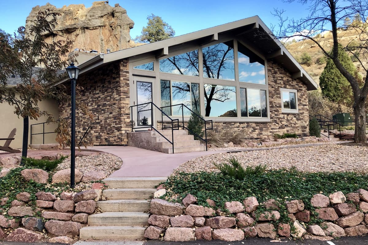 Un moderno edificio de piedra con grandes ventanales y una escalera de piedra que lleva a la entrada.