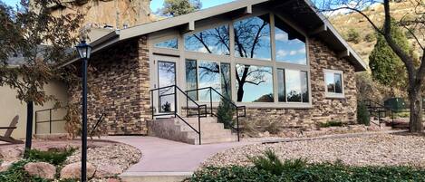 A modern stone building with large windows and a stone staircase leading to the entrance.