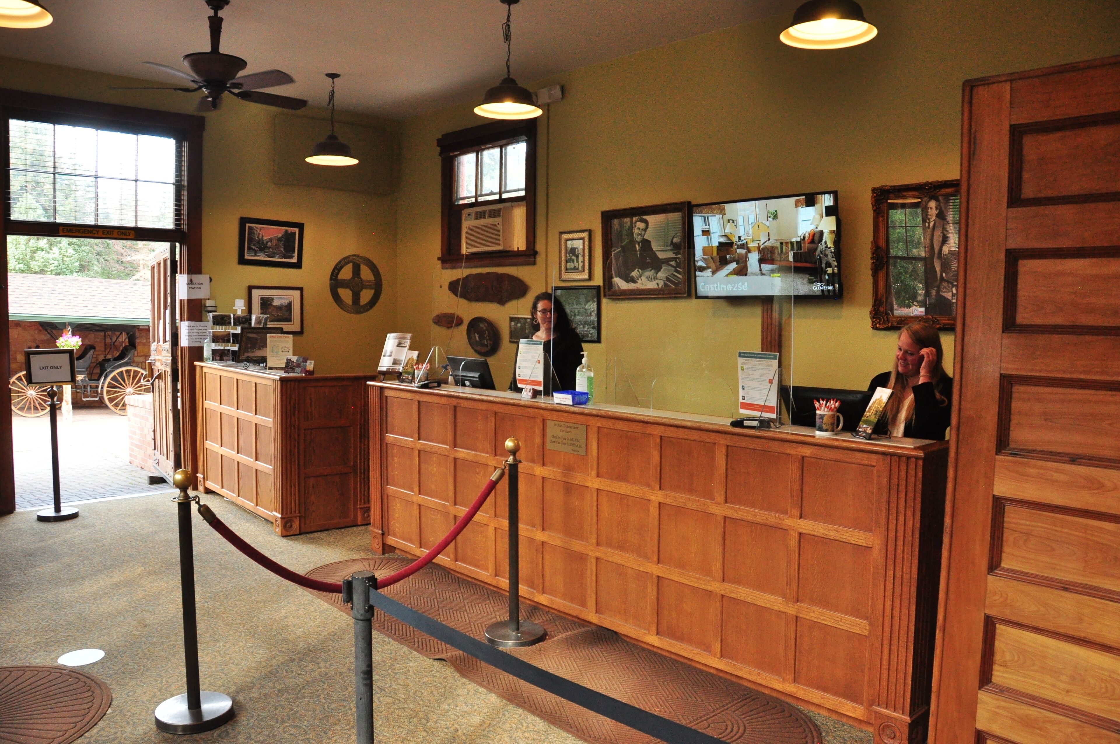 A reception area with a wooden counter, a ceiling fan, and framed pictures on the wall.