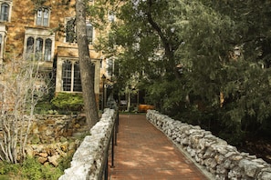 A stone pathway flanked by trees and a stone wall, leading to a building with arched windows and a stone facade. - Glen Eyrie Castle & Conference Center A Ministry of the Navigators (Colorado Springs)