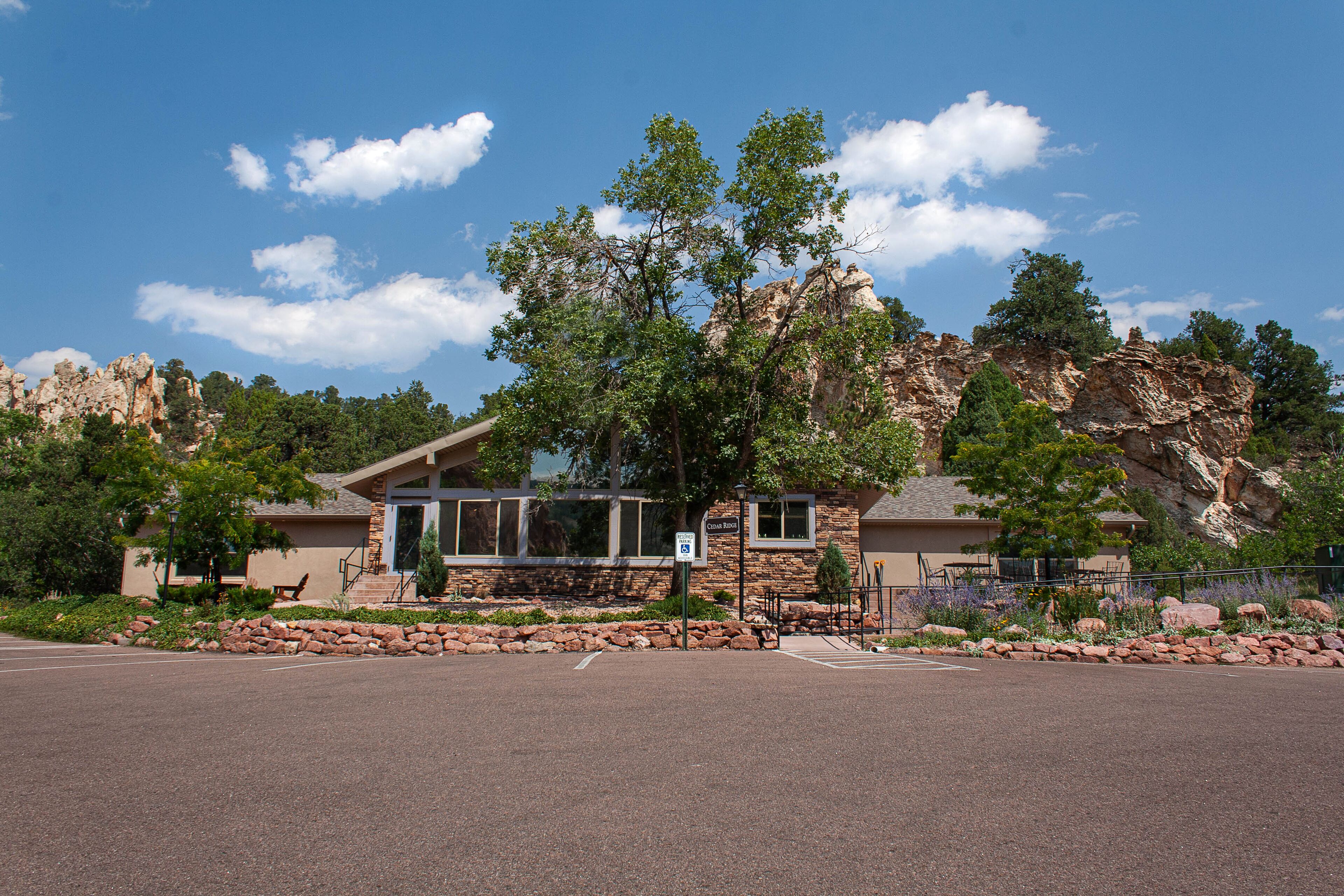 A building with a stone facade, large windows, and a view of a rocky landscape.