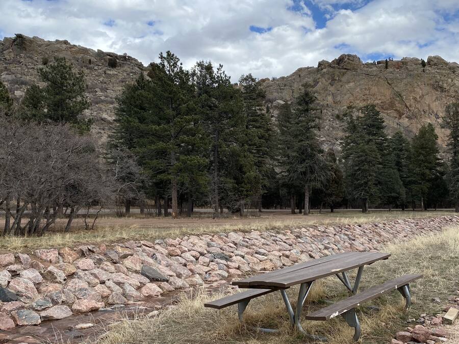 Une table de pique-nique installée dans un cadre naturel, avec une colline rocheuse et des arbres en arrière-plan.