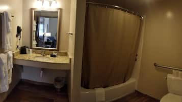 A bathroom with a shower curtain, a sink with a mirror, and a toilet.