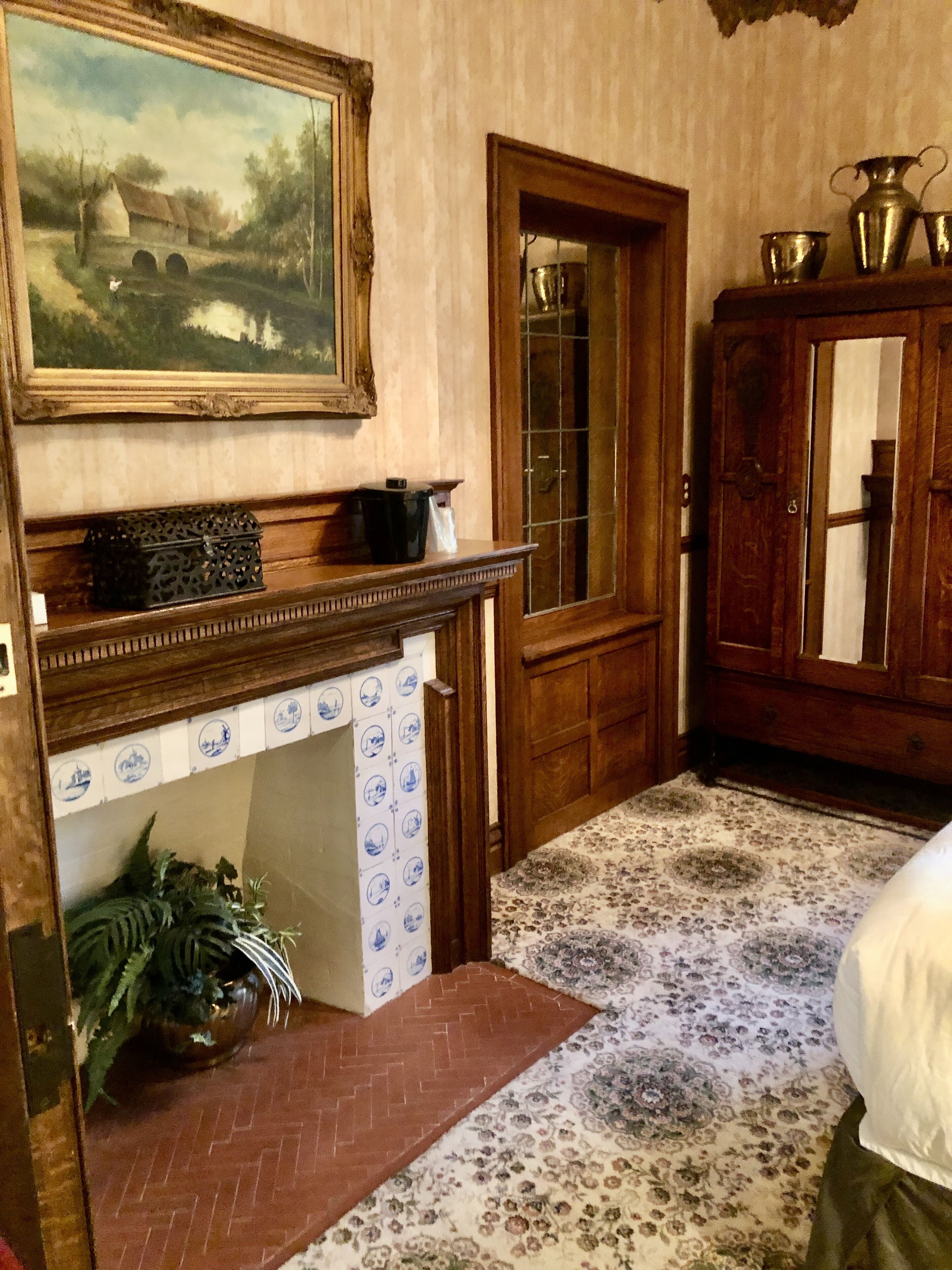 Una habitación con chimenea, un aparador de madera, un cuadro y una alfombra estampada.