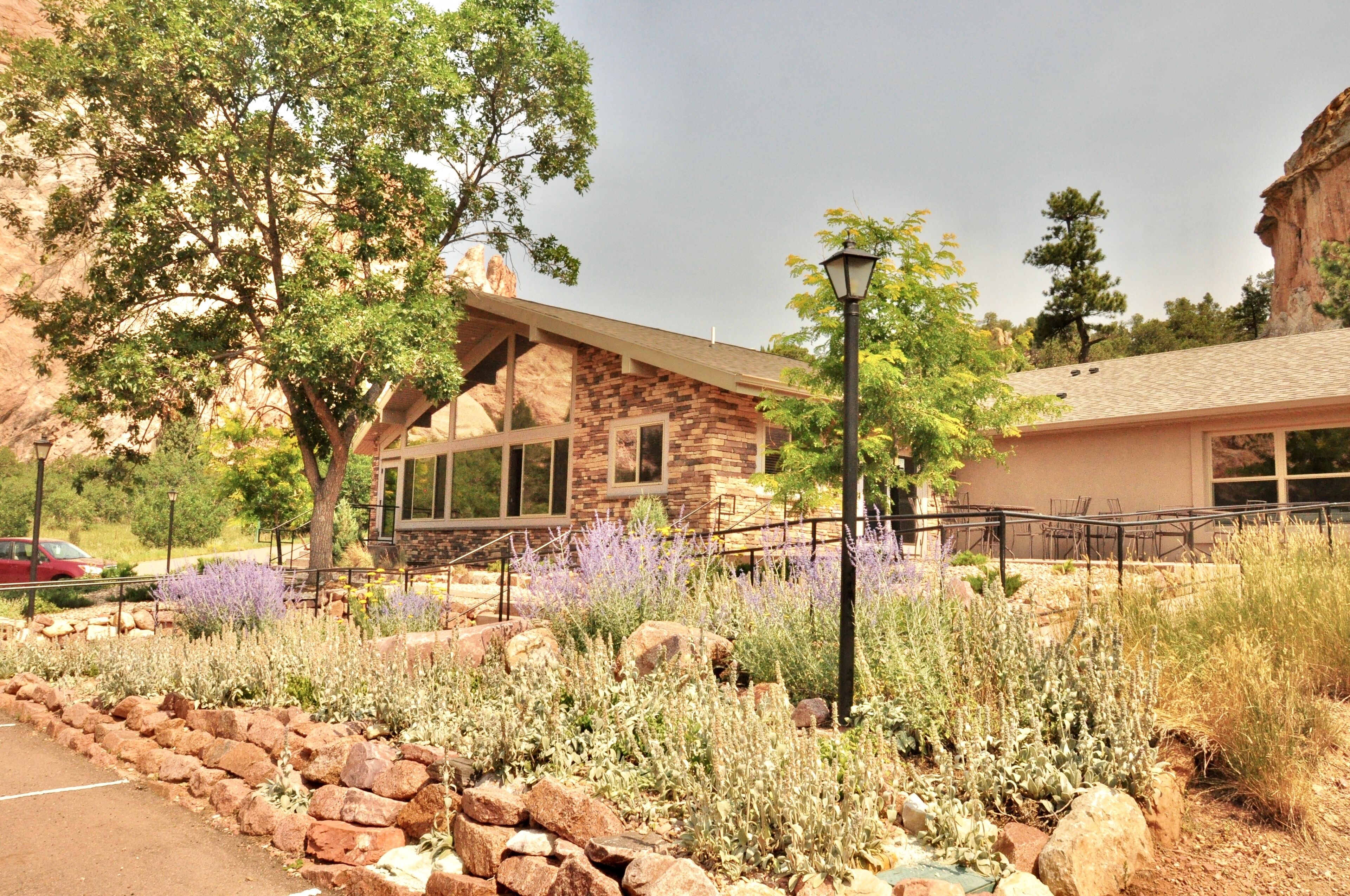 A stone building with a modern design, surrounded by a landscaped garden with various plants and a paved walkway.