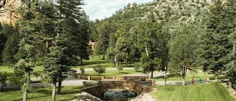 Un parcours de golf avec un ruisseau, des arbres et une montagne en arrière-plan.