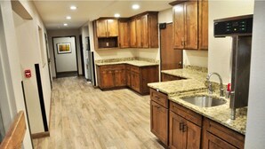 A kitchen with wooden cabinets, granite countertops, and stainless steel appliances. - Glen Eyrie Castle & Conference Center A Ministry of the Navigators (Colorado Springs)