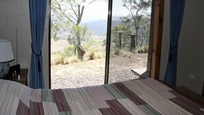 A room with a bed, a lamp, and a view of a natural landscape through large windows. - The gallery - eco-friendly atmosphere (Vacy)