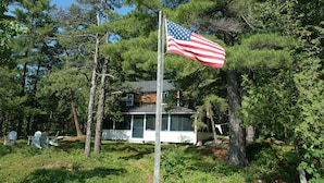 Une maison entourée d’arbres, avec un drapeau américain flottant au sommet d’un mât.