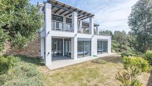 A modern two-story house with a stone foundation, large glass windows, and a balcony. - Minimal Maisonette In Porto Cheli (Porto Cheli)