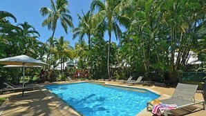 A swimming pool surrounded by palm trees, with lounge chairs and umbrellas. - Port Douglas Mirage Villa 408 (Port Douglas)