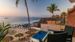 A beachfront hotel with a pool, lounge chairs, and a view of the ocean.