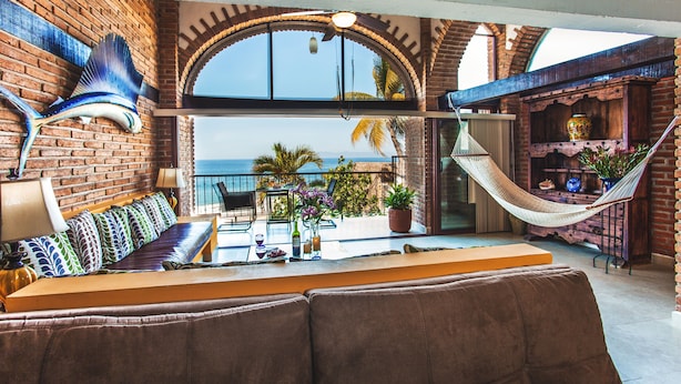 A spacious balcony with a view of the sea, a hammock, and a seating area with a table and chairs.