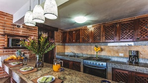 A kitchen with granite countertops, wooden cabinets, a gas stove, and a coffee maker.