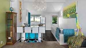 Une cuisine moderne avec des meubles blancs, un îlot central et un luminaire suspendu.