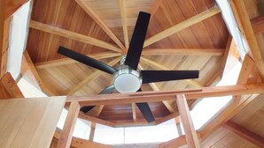 Techo de madera con ventilador central y vigas a la vista.