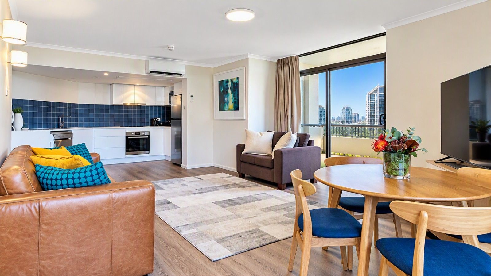 A modern apartment with a kitchen, living area, and balcony with a city view.