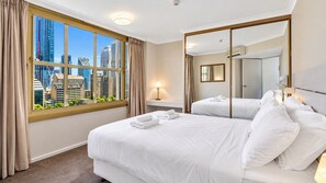 Ein Hotelzimmer mit großem Fenster, einem Bett, einem Nachttisch mit Lampe und einem Spiegel.
