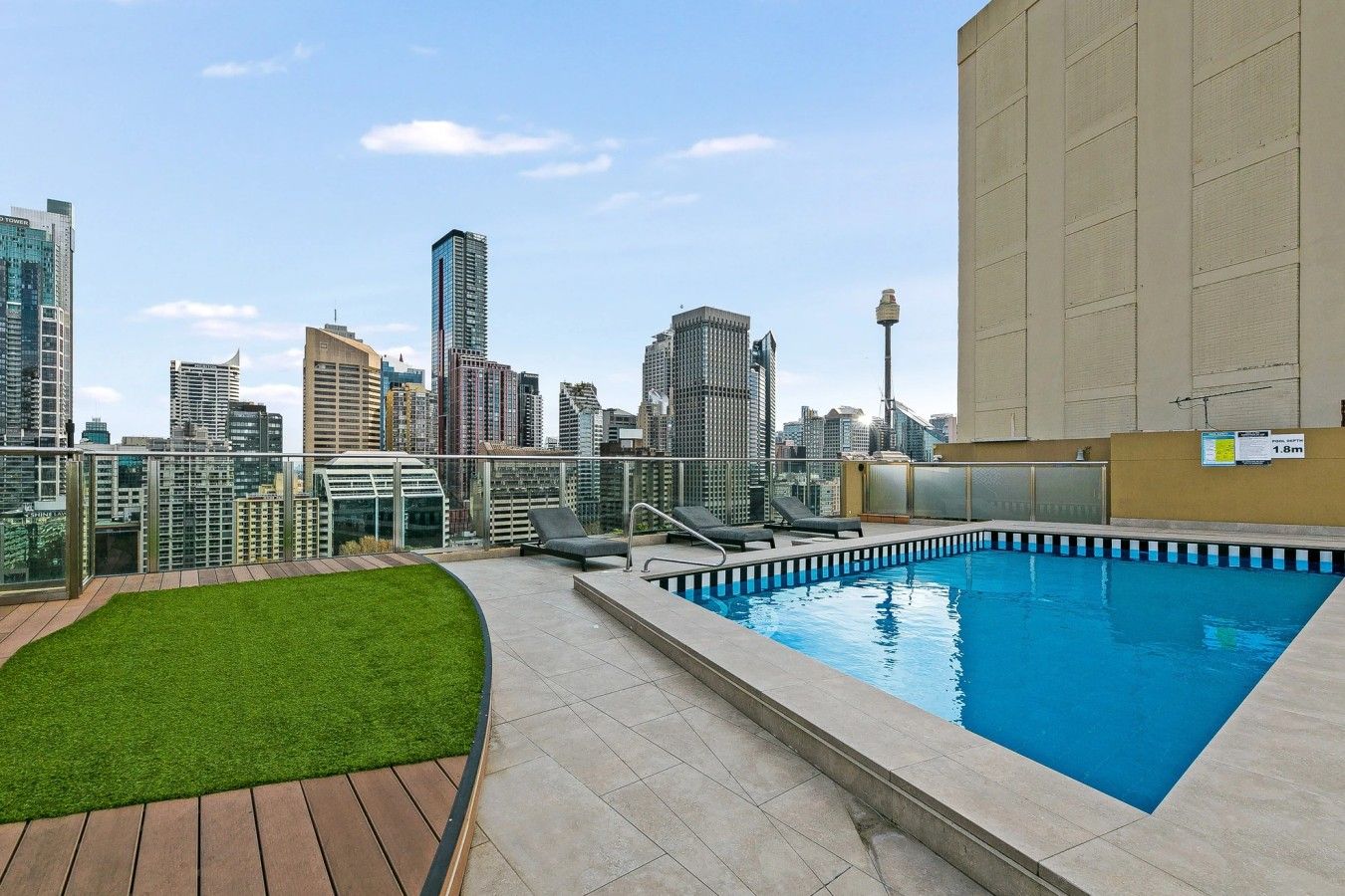 A rooftop pool with lounge chairs and a city skyline view.