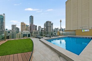 Ein Pool auf dem Dach mit Liegestühlen und Blick auf die Stadtlandschaft.