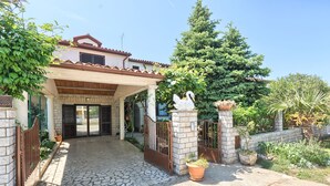 A house with a stone-paved entrance, a covered porch, and a gated driveway. - Spacious holiday apartment, only 1km from the beach (Valbandon, Fažana)