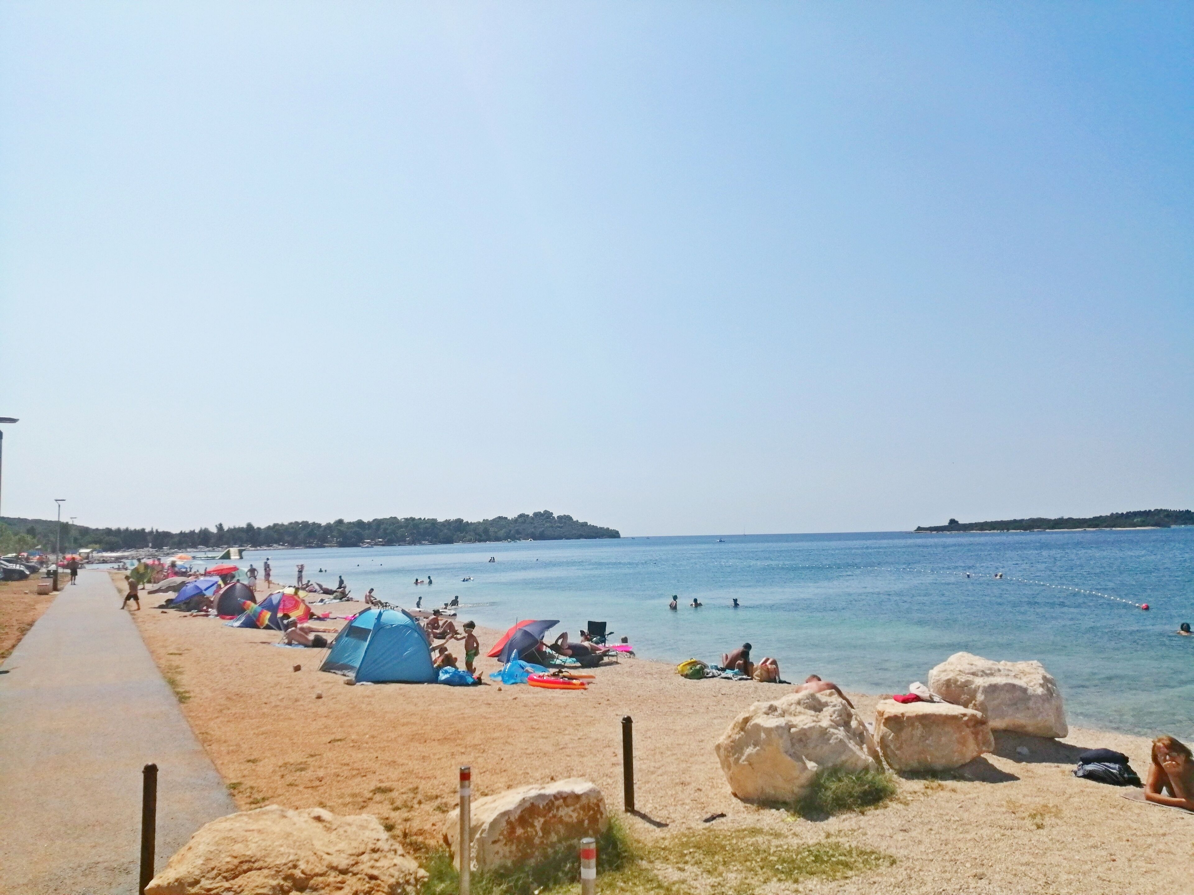 A beach with tents, people, and a clear sky.
