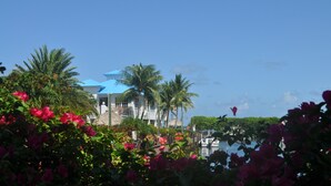 A resort with a large building, palm trees, and a view of the water. - Oceanfront, 2 Bedroom Unit At Ocean Pointe Condominium (Tavernier)