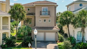Een meerlaags woongebouw met garage, omringd door palmbomen en een verzorgd gazon.