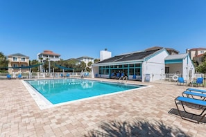 Ein Pool mit Liegestühlen und einer überdachten Liegefläche, umgeben von Gebäuden.