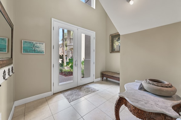 A hallway with a white door, a bench, a decorative table, and a rug.